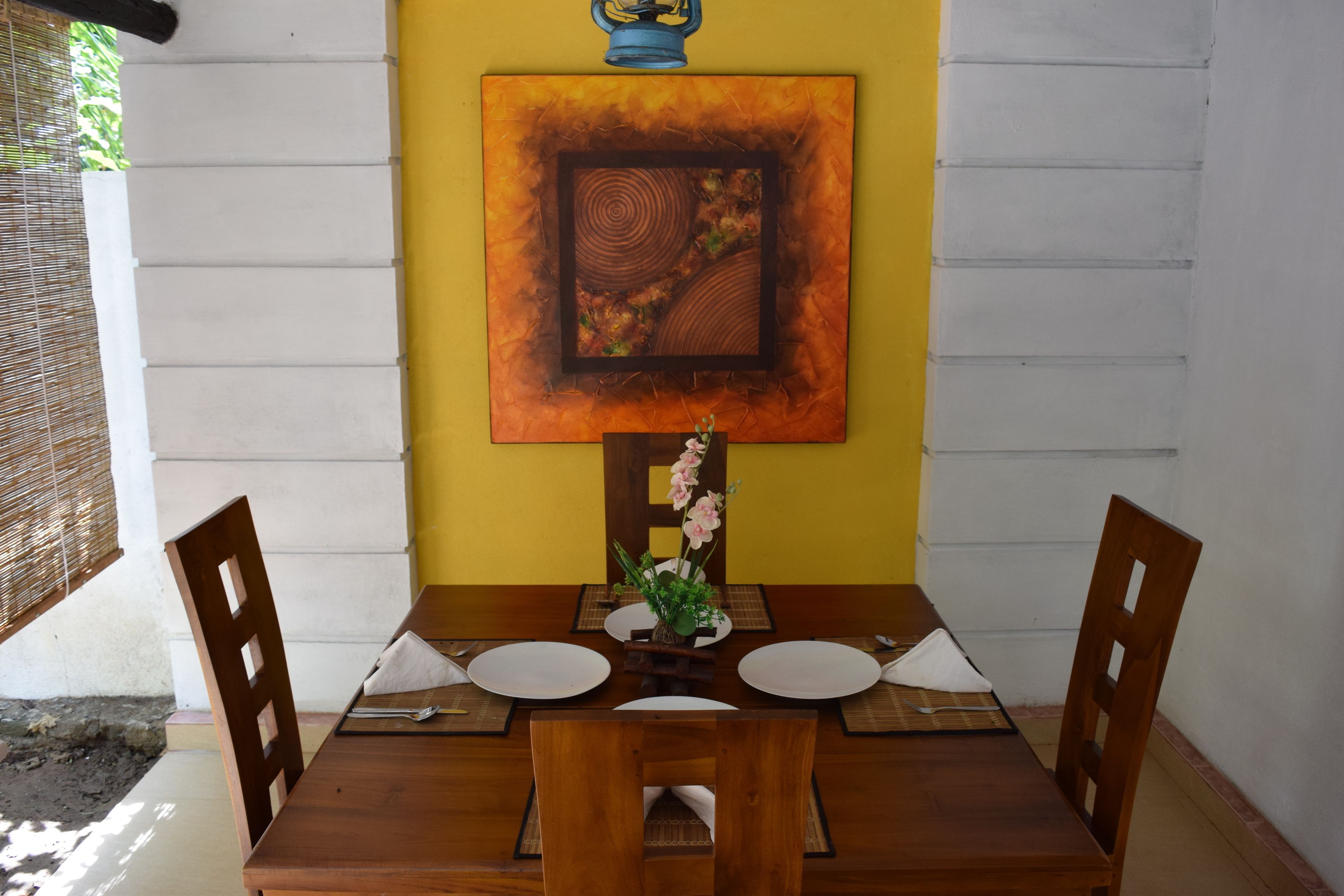Taula de dinar coberta per a dues persones, amb acabat de fusta, un ram de flors i una obra d'art emmarcada a la paret.
