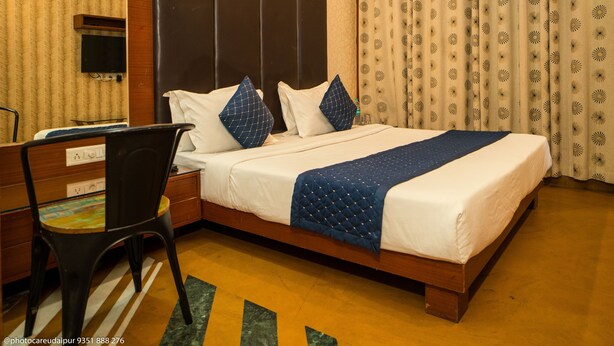 A hotel room with a large bed, a desk, and a chair. - Uddhav Vilas (Udaipur)