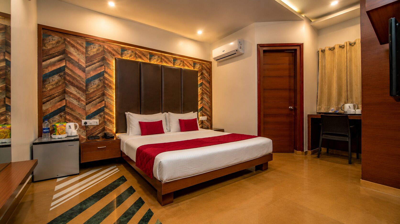 A hotel room with a bed, bedside table, nightstand, and a desk with a chair.