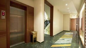 A modern hallway with a marble floor, an elevator, and a staircase leading to another floor. - Uddhav Vilas (Udaipur)
