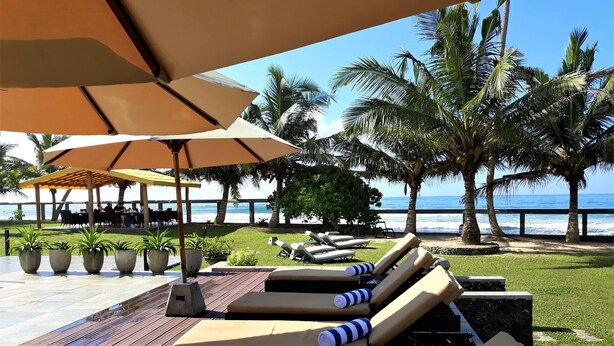 A beachside lounge area with sun loungers, umbrellas, and potted plants. - Imagine Villa Hotel (Kamburugamuwa)