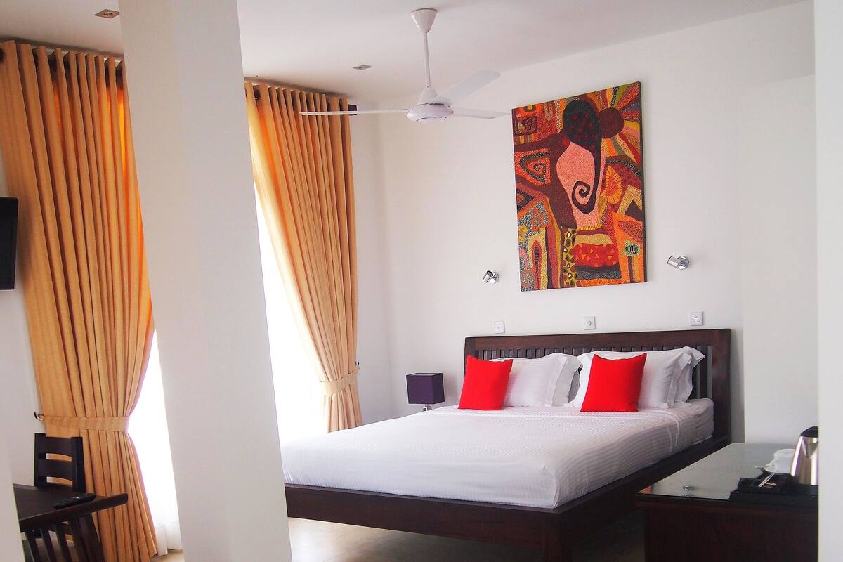 Una habitación de hotel con una cama grande, un escritorio, una silla y un cuadro en la pared.