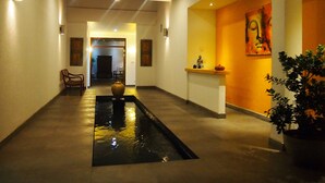 A hallway with a water feature, a reception desk, and artwork on the walls. - Imagine Villa Hotel (Kamburugamuwa)