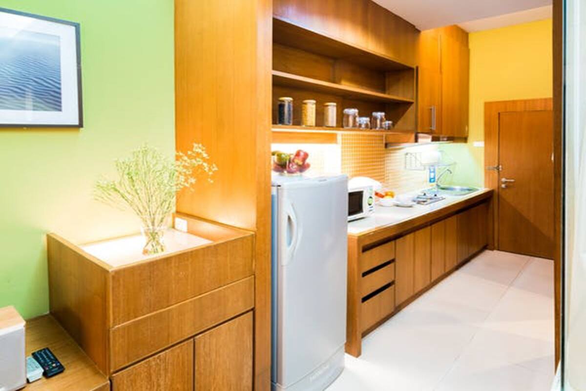 A kitchen with wooden cabinets, a refrigerator, a microwave, and a sink.