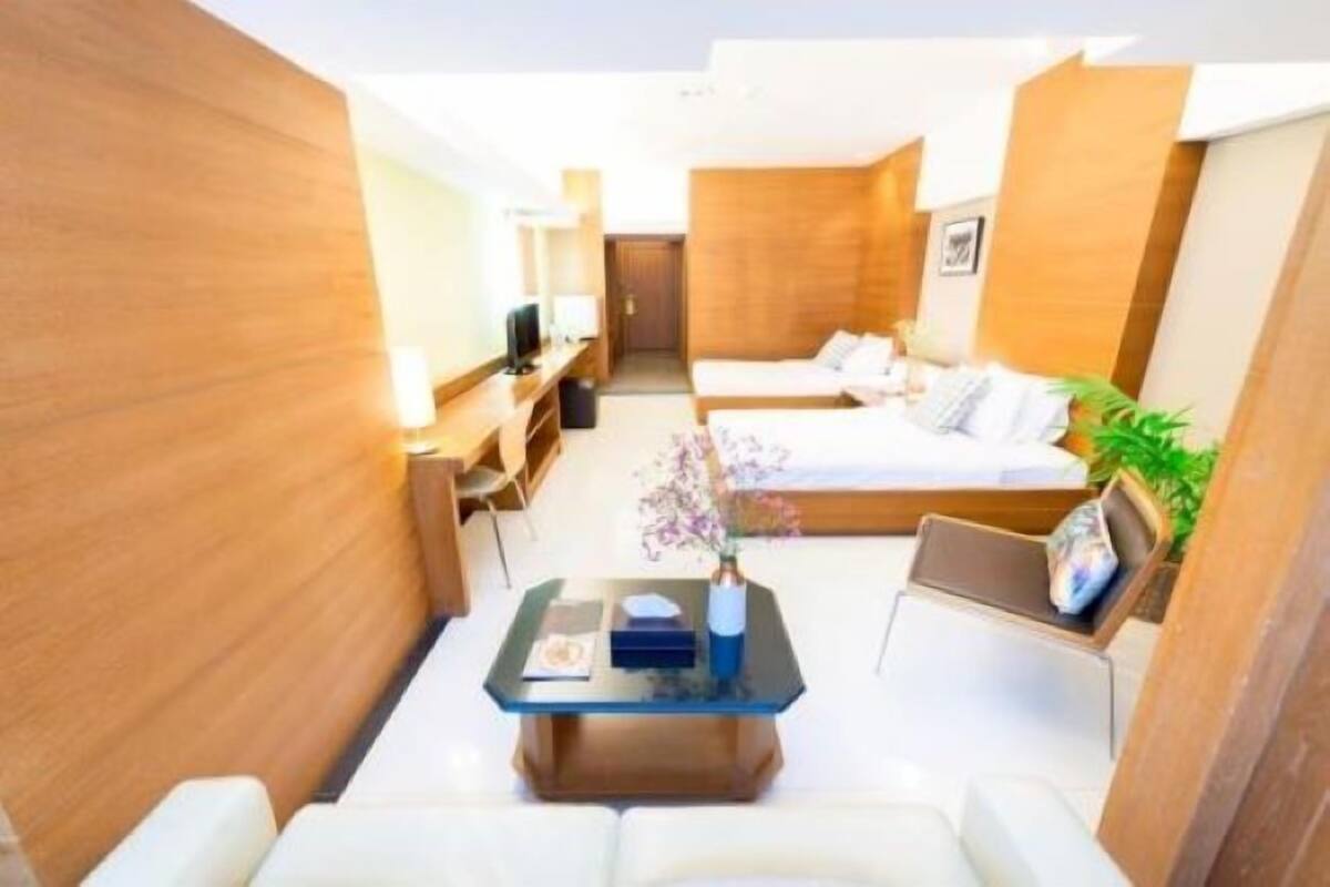 A compact hotel room with a bed, a small desk, a chair, and a coffee table.
