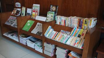 Een boekenkast met diverse boeken en tijdschriften, netjes gerangschikt op houten planken.