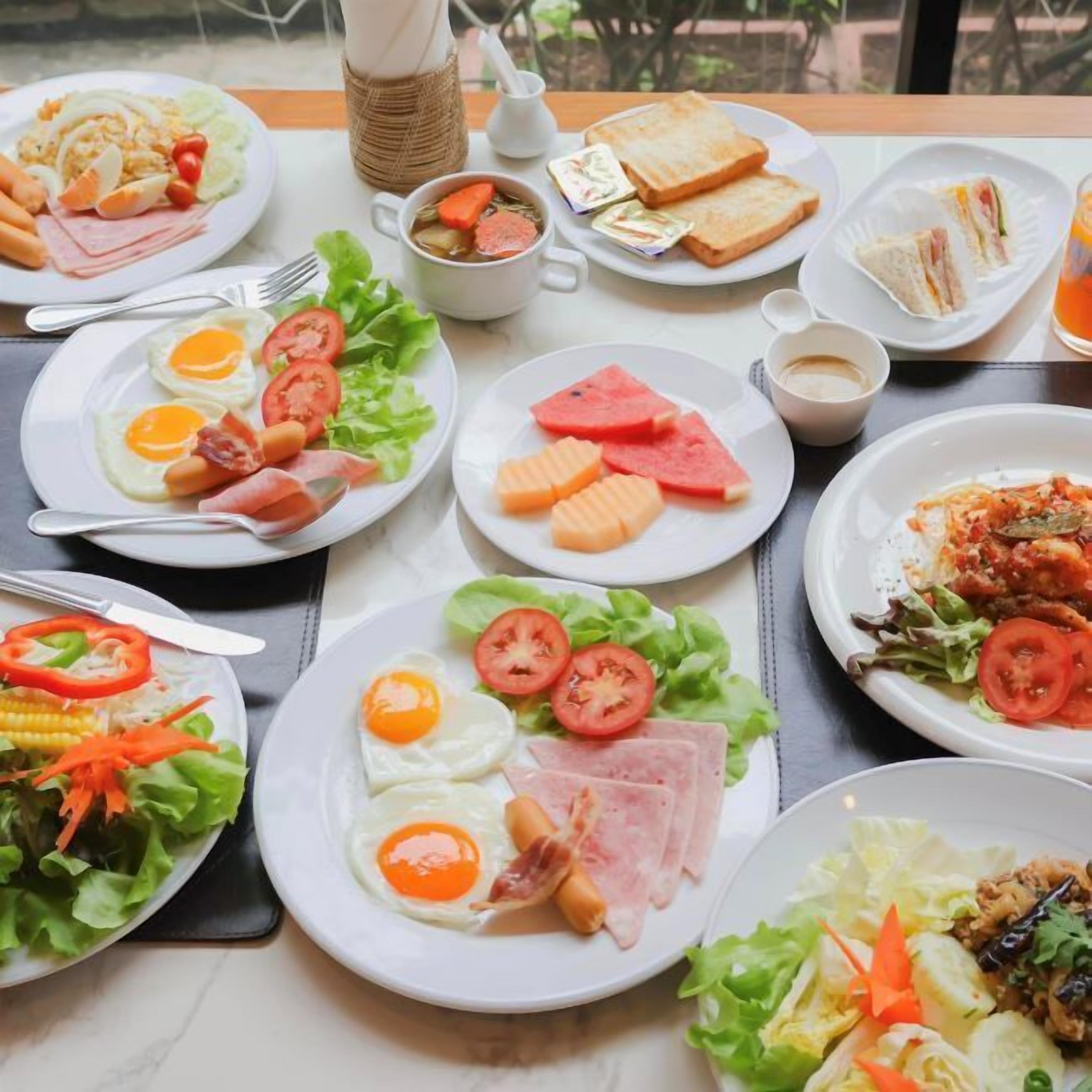 Una mesa dispuesta con diversos platos de desayuno, incluyendo huevos, tostadas y ensaladas.