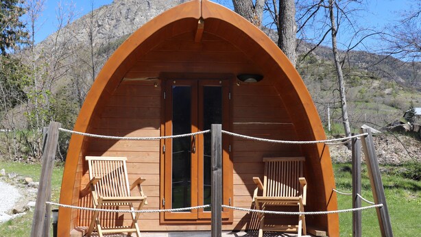Eine Holzhütte mit gewölbtem Dach, zwei Holzstühle davor und eine Seilsperre.