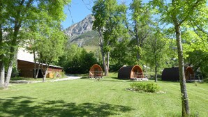 Ein Campingplatz mit mehreren Holzhütten, einer Rasenfläche und einem Berg im Hintergrund.