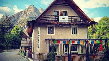 Experience the charm of the Alps at Le Martagon Hotel, where a traditional wooden balcony and pitched roof meet stunning mountain views.