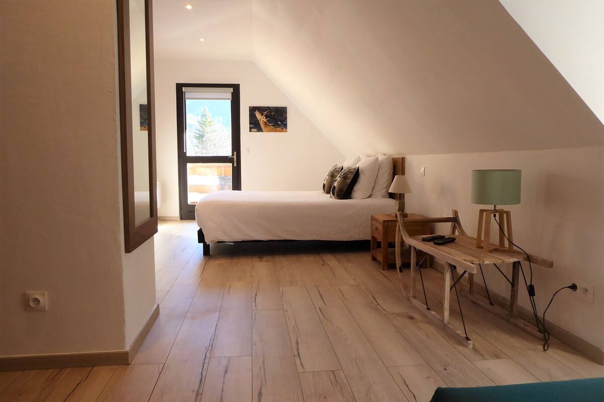 A bedroom with a bed, a nightstand, a lamp, and a window.