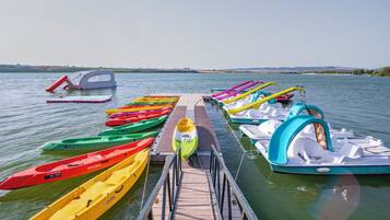Un muelle con coloridos canoas y un pequeño bote.
