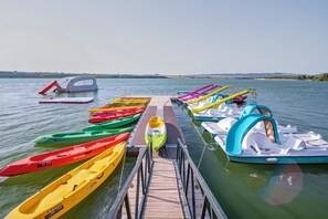 Um cais com canoas coloridas e um pequeno barco.