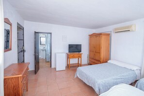 A bedroom with a bed, a wooden dresser, a television, a wardrobe, and a small white refrigerator. - La Molinera Bungalows (Arcos de la Frontera)