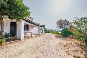 Un edificio blanco con techo de tejas, camino de grava y vistas del paisaje.