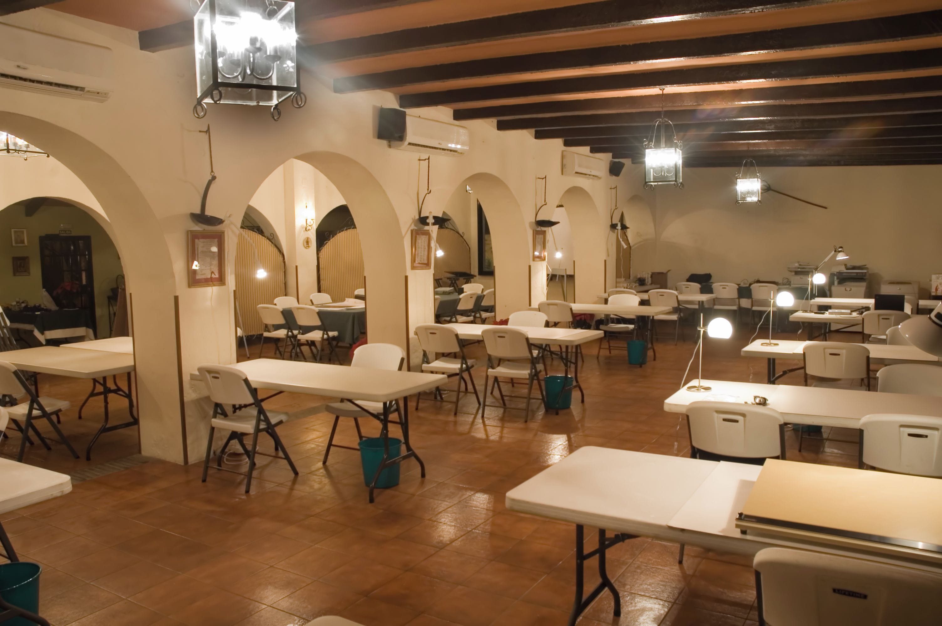 A dining area with tables and chairs, arched ceilings, and hanging lights.