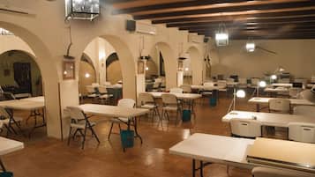 A dining area with tables and chairs, arched ceilings, and hanging lights.