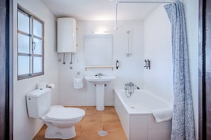 A bathroom with a toilet, sink, bathtub, and a window. - La Molinera Bungalows (Arcos de la Frontera)