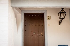Une porte marron avec un panneau indiquant le numéro « 2 » au-dessus, un luminaire fixé au mur et un tuyau bleu visible sur la droite.