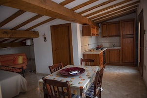A cozy kitchen with wooden cabinets, a dining table with chairs, and a small kitchenette.