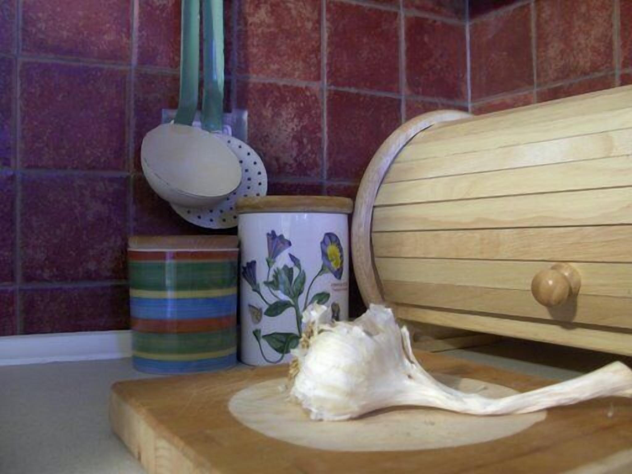 A kitchen counter with a wooden cutting board, a ceramic mug with floral design, and a striped container.