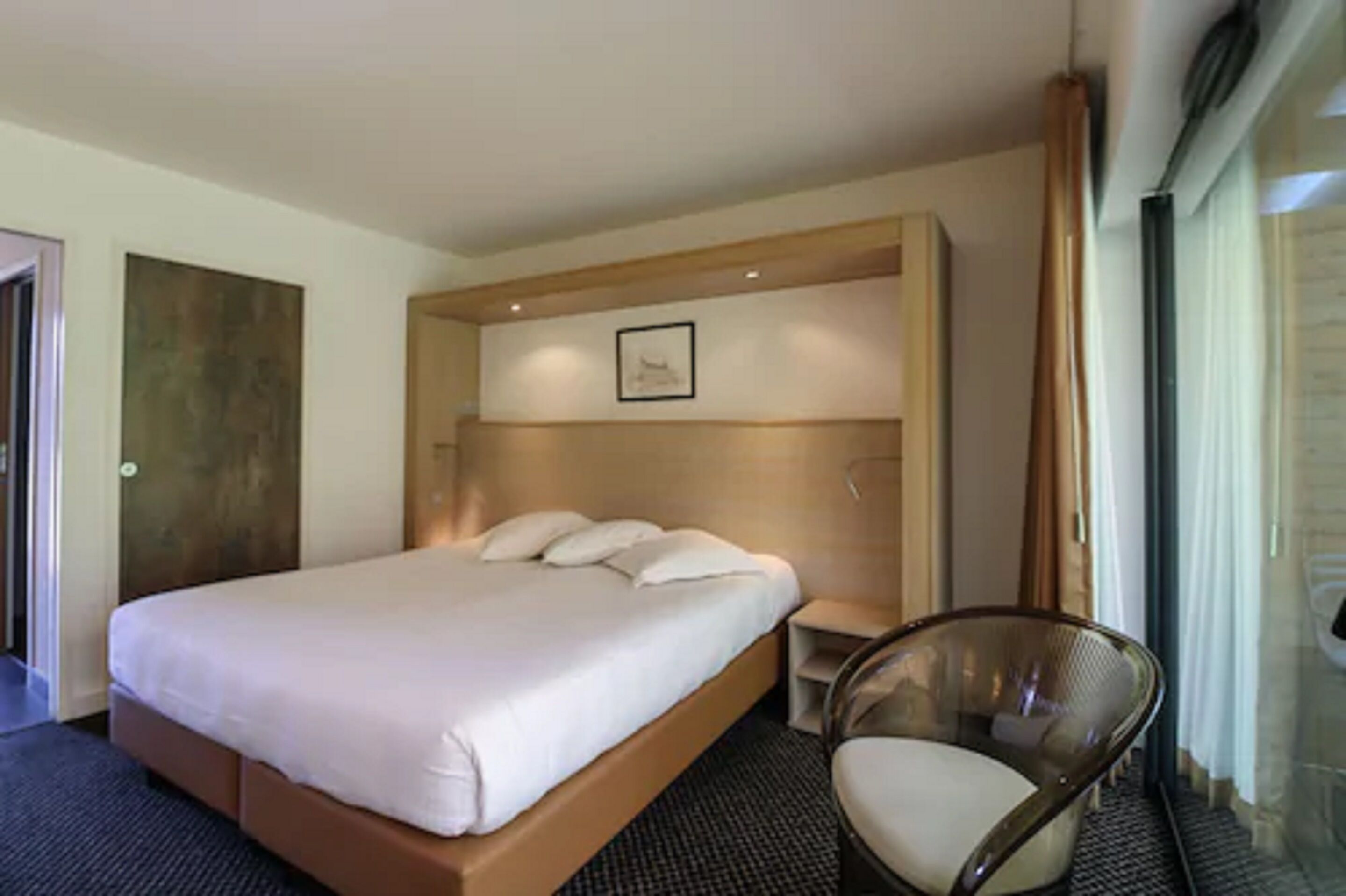 Une chambre d’hôtel avec un grand lit, une chaise et une petite table.