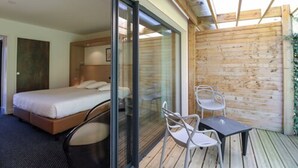 A modern bedroom with a large bed, a glass door leading to a balcony, and a small table with chairs. - Loire & Sens (Les Garennes-sur-Loire)