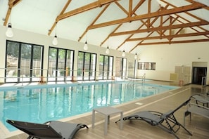 Relax by the pool surrounded by lounge chairs and a table, with a clear view of the water.