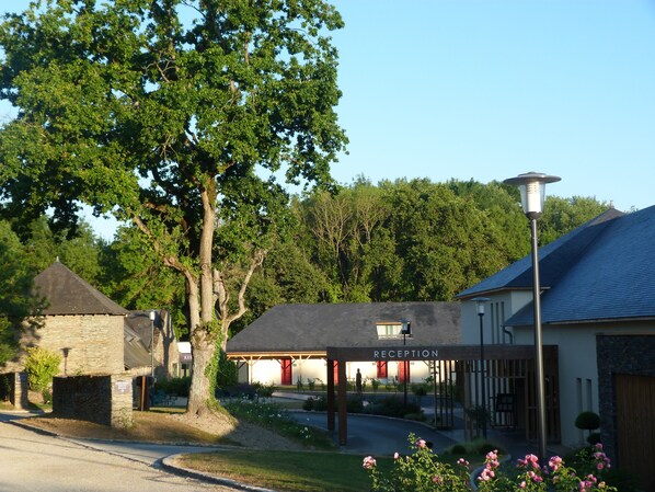 A reception area with a sign, a stone building, and a tree. - Loire & Sens (Les Garennes-sur-Loire)