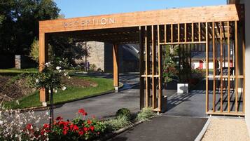 Un espace d’accueil agrémenté d’une pergola en bois et d’une enseigne indiquant « RÉCEPTION ».
