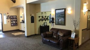 A lobby with a leather sofa, a mounted deer head, a bookshelf, and a framed picture on the wall. - Blue Spruce Inn (Meeker)