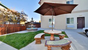 A patio with a table and chairs, a decorative fountain, and a large umbrella. - Blue Spruce Inn (Meeker)