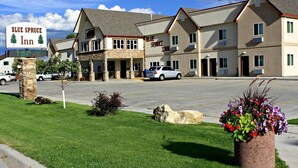 A Blue Spruce Inn with a stone facade, multiple balconies, and a parking lot. - Blue Spruce Inn (Meeker)