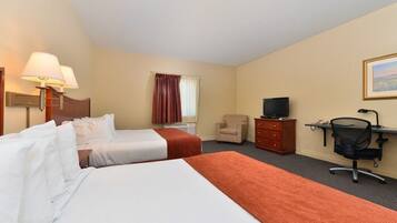 A hotel room with two beds, a desk, a chair, a television, and a window with curtains.