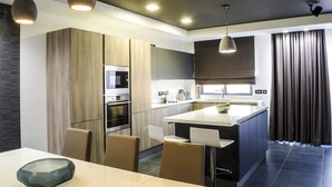 A modern kitchen with a central island, built-in appliances, and pendant lighting. - Paramount Bay Penthouse (Birzebbuga)