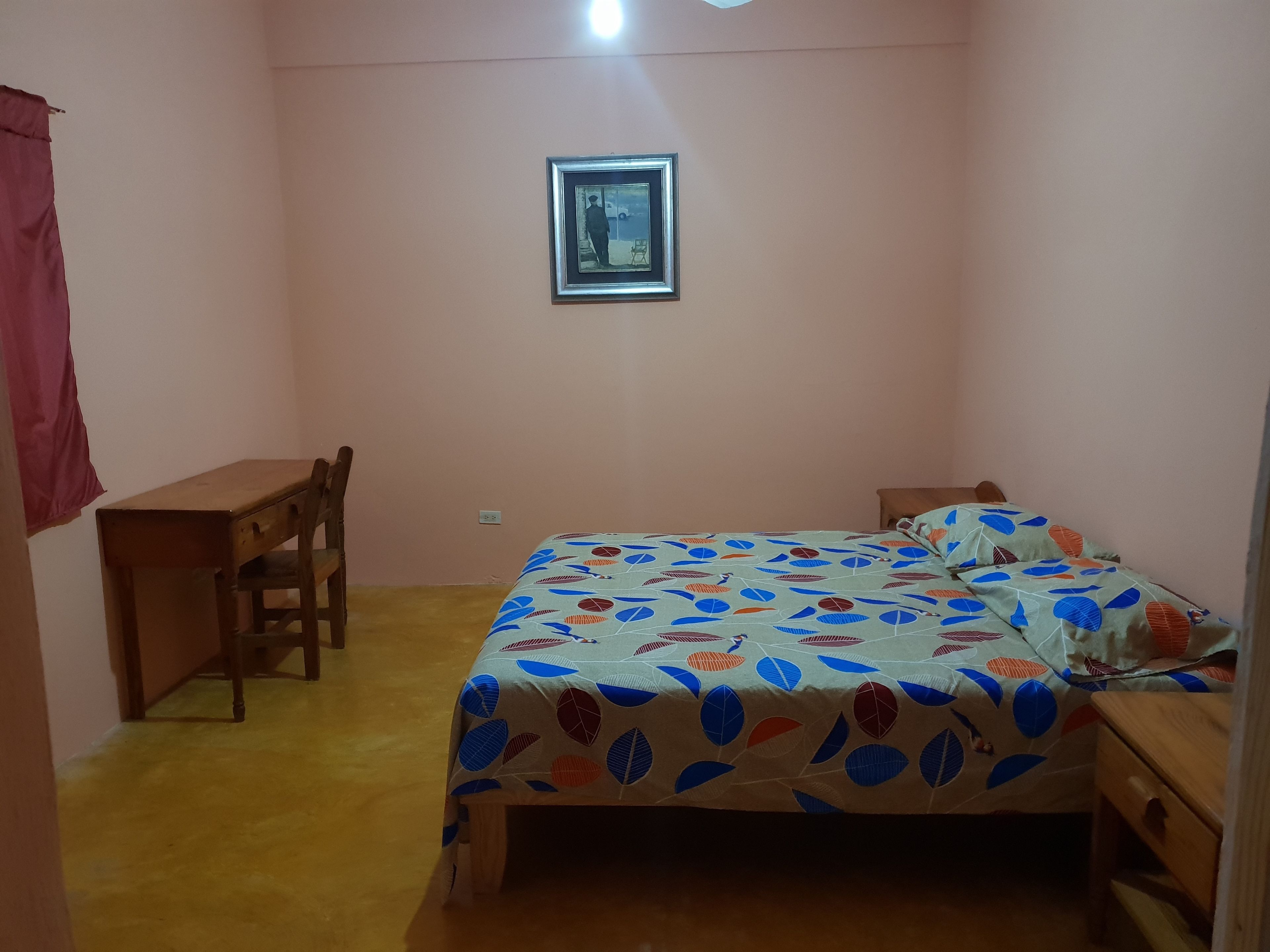 A bedroom with a bed, a desk, and a chair.