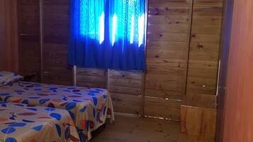 Una habitación de madera con cama y ventana con cortinas azules.
