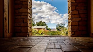 An arched stone doorway leading to an outdoor area with a clear sky and clouds.