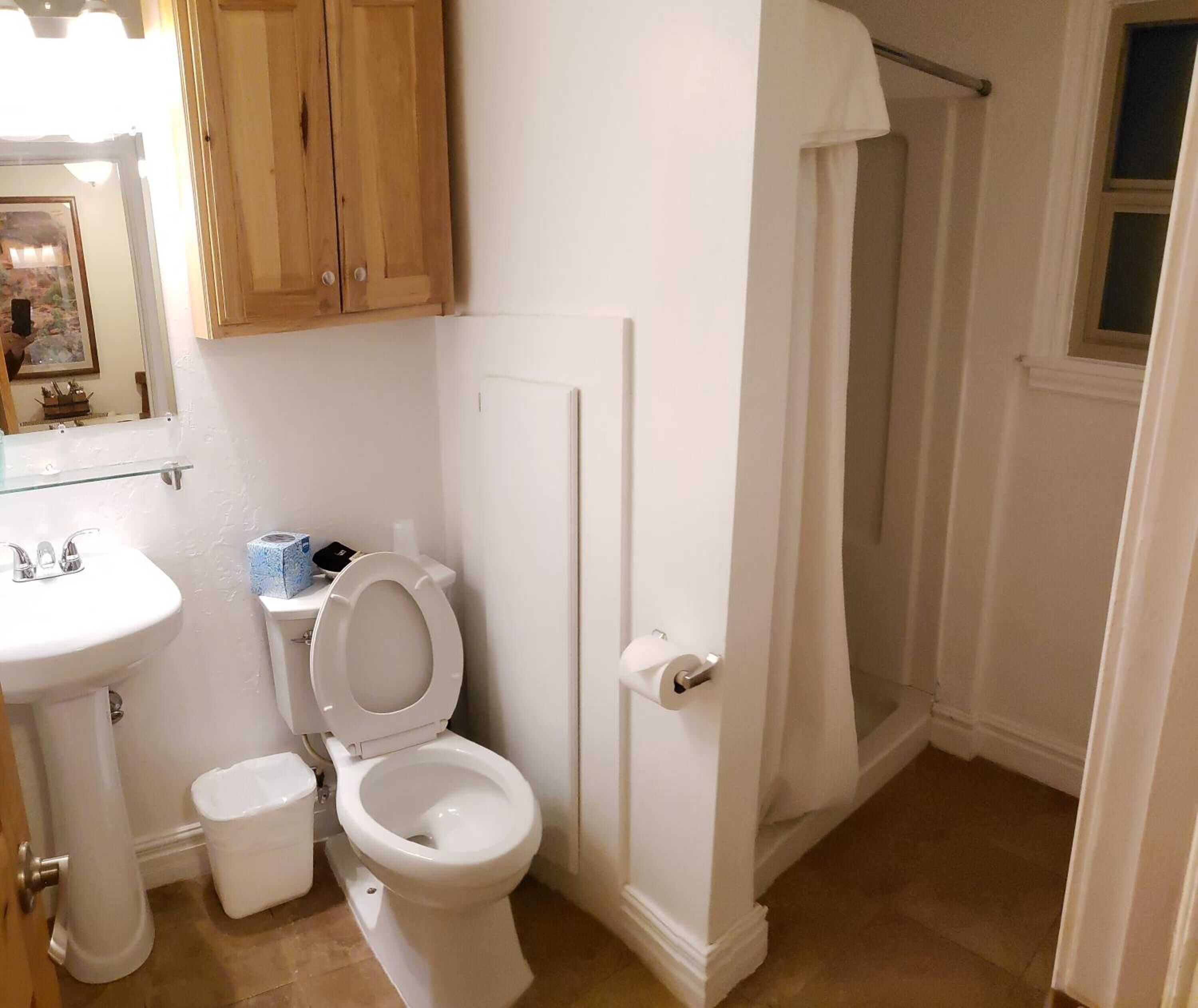 Une salle de bain comprenant des toilettes, un lavabo et un espace douche.