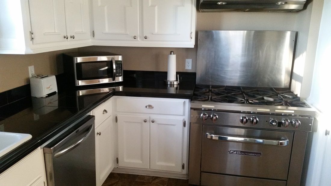 A kitchen with white cabinets, a stainless steel microwave, a gas stove, and a dishwasher.
