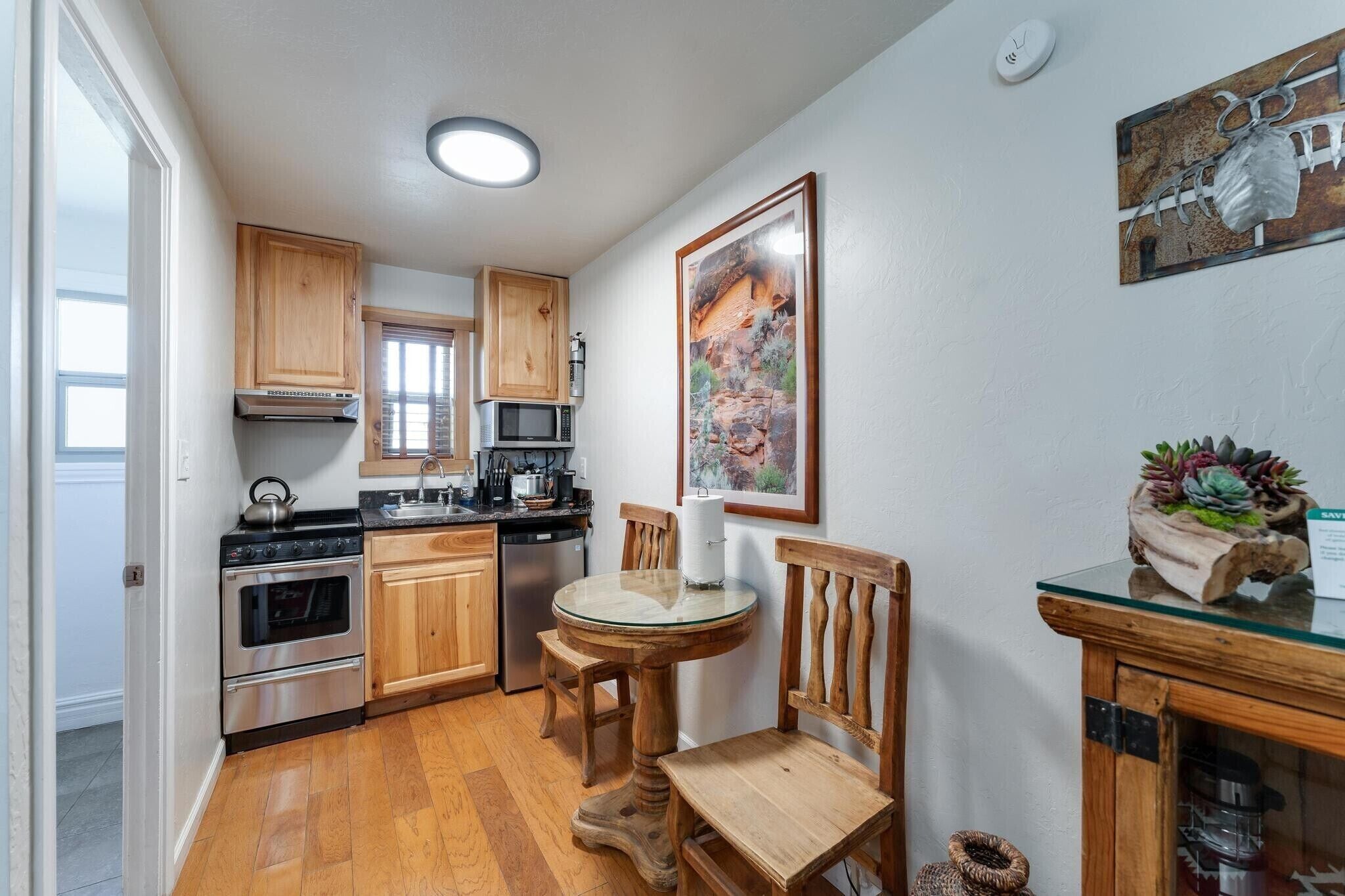 A kitchen with wooden cabinets, a stove, a microwave, and a glass table with chairs.