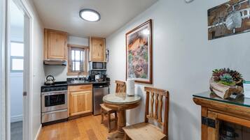 A kitchen with wooden cabinets, a stove, a microwave, and a glass table with chairs.
