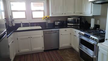 A modern kitchen with white cabinets, stainless steel appliances, a dishwasher, a stove, and a microwave.