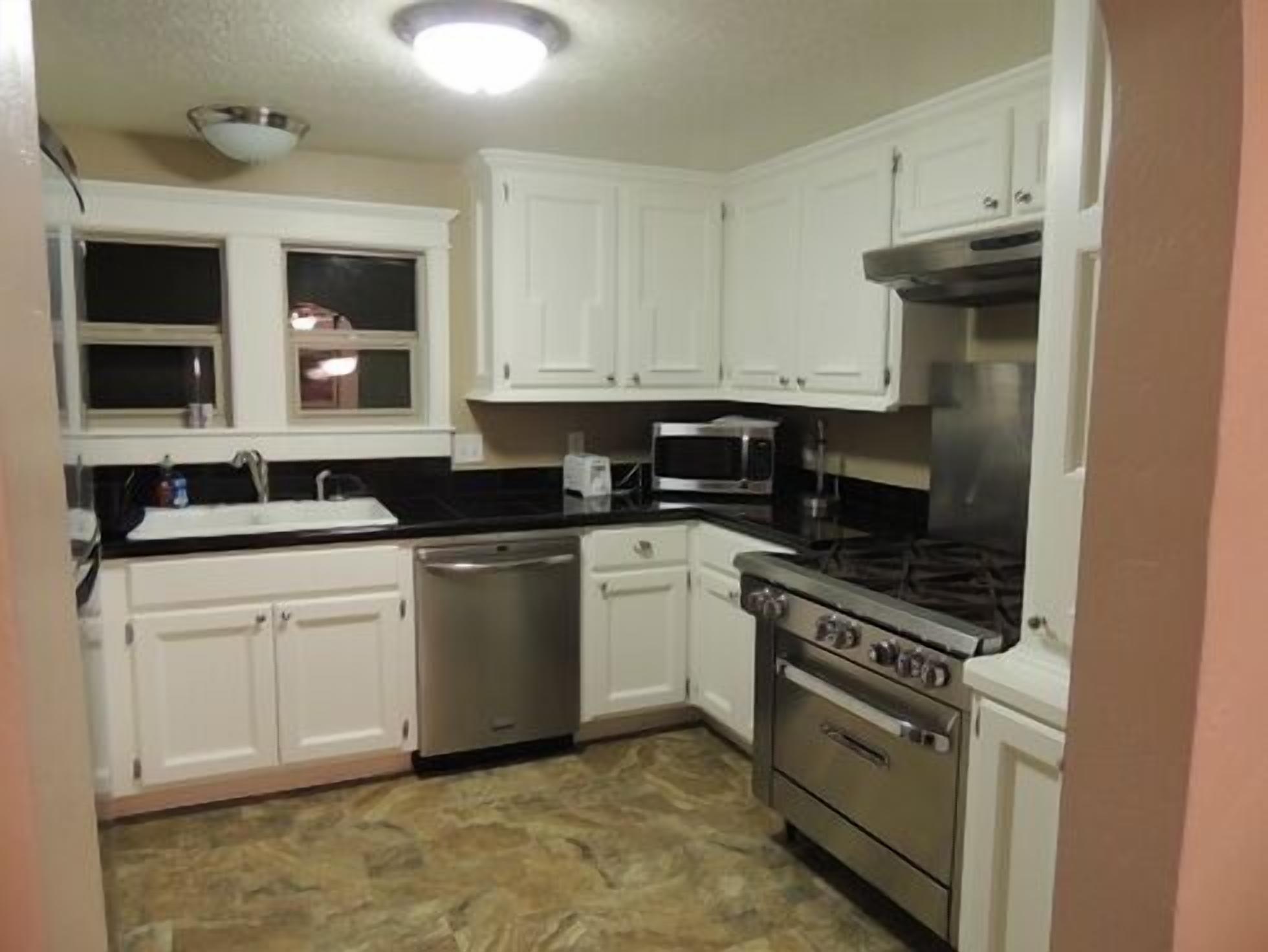 A kitchen with white cabinets, a stainless steel dishwasher, a microwave, and a stove.