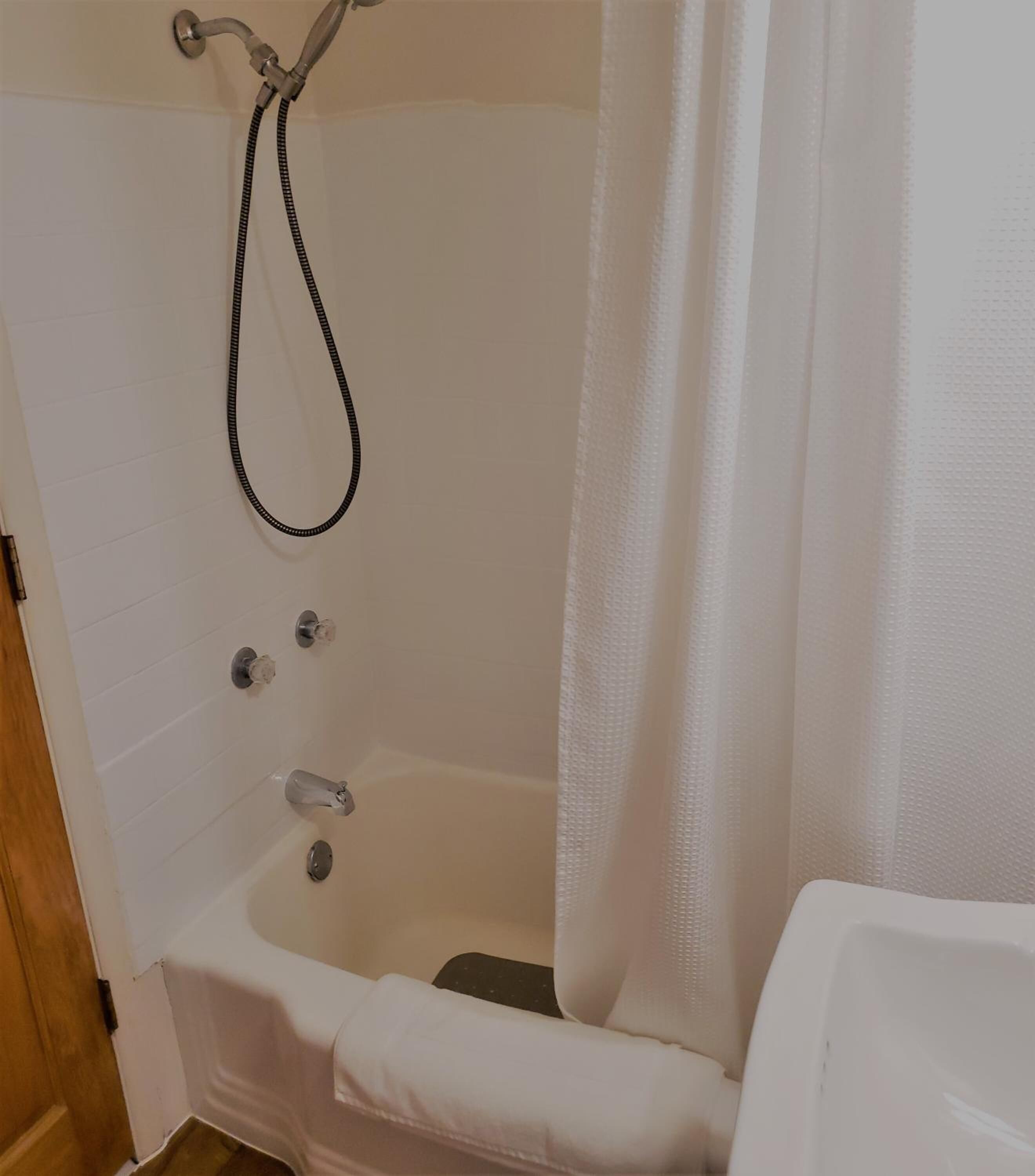 A bathroom with a bathtub, a showerhead, and a curtain.