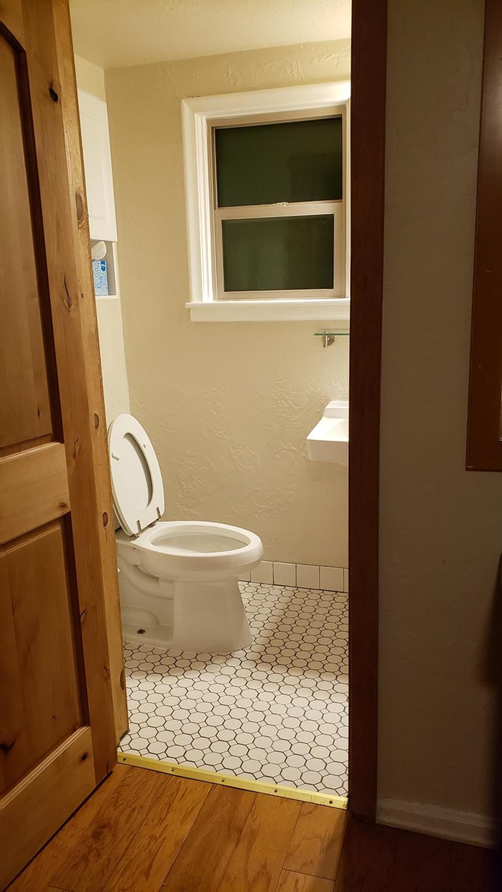 A bathroom with a toilet, a window, and a sink.