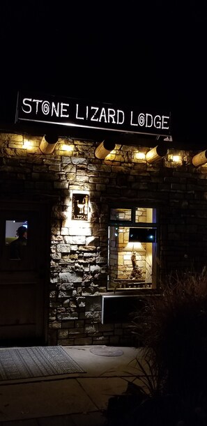 The exterior of Stone Lizard Lodge with a stone facade, illuminated windows, and a sign above the entrance.