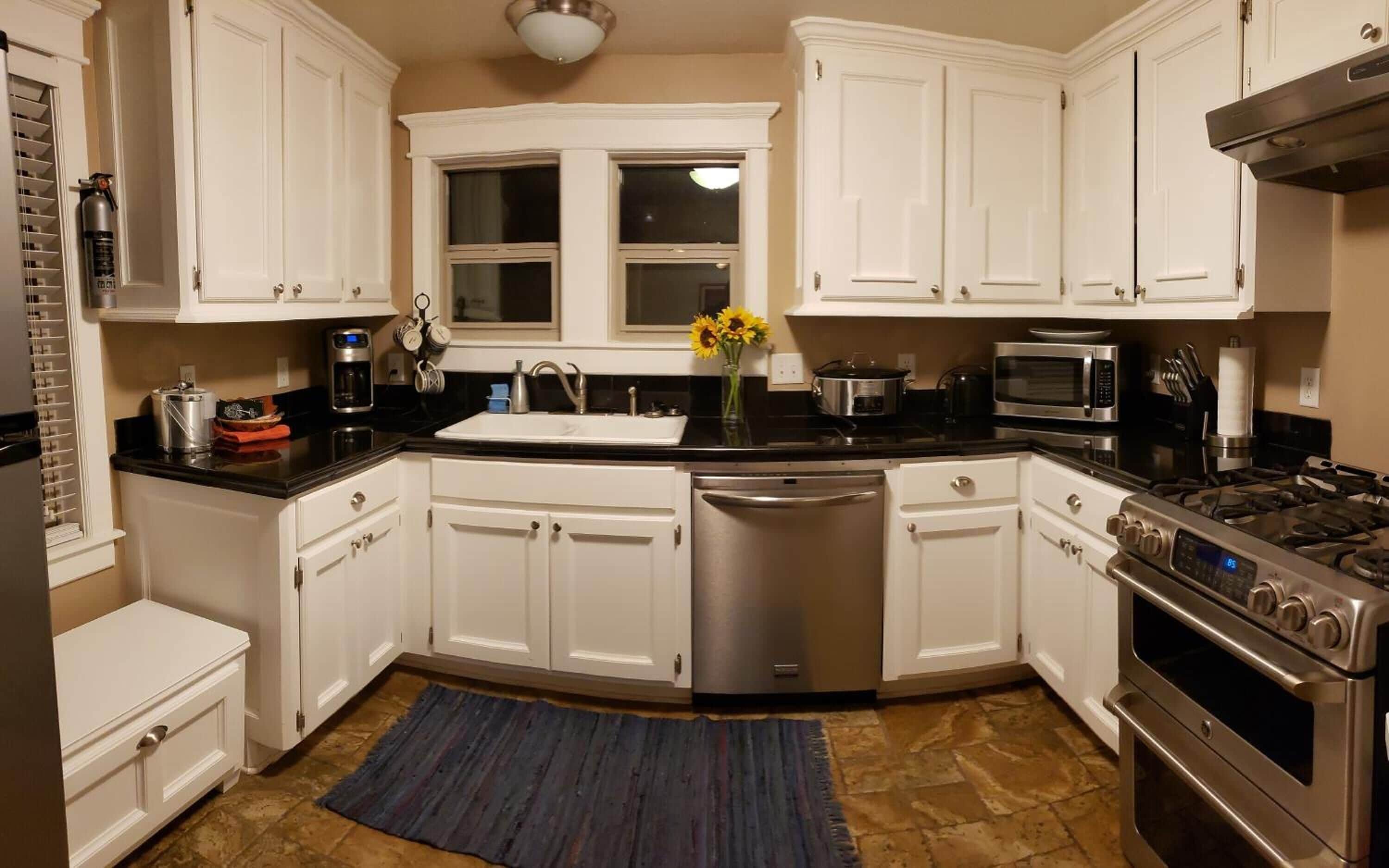A modern kitchen with white cabinetry, a stainless steel dishwasher, a gas stove, and a microwave.