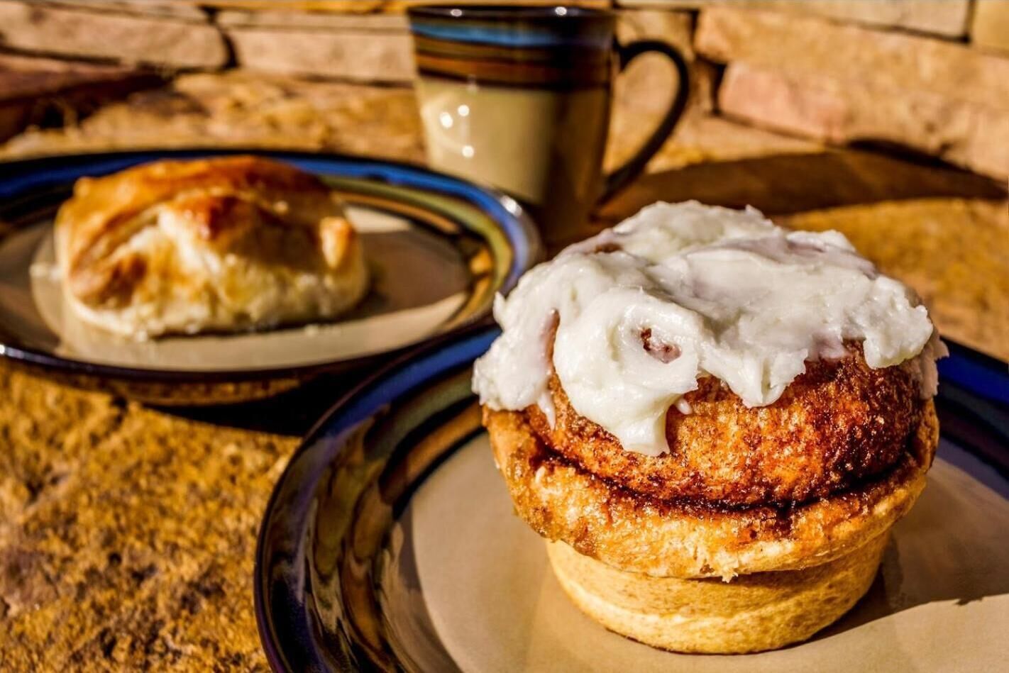 Un muffin surmonté d’une garniture crémeuse, présenté sur une assiette, avec un autre muffin visible en partie à l’arrière-plan.