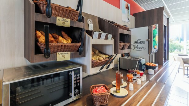Une vitrine de boulangerie présentant du pain et des pâtisseries, une machine à café et un distributeur de jus.